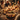 A warm, inviting close-up shot of a holiday dinner table, centered on a golden-brown roasted chicken garnished with rosemary and roasted potatoes. The rustic wooden table is adorned with numerous lit candles, glasses of white wine, and various side dishes. In the blurred background, several people, including elderly individuals, are visible, suggesting a family or friends gathering for a festive meal.
