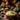 A rustic bowl of mashed potatoes topped with rosemary sits on a burlap cloth surrounded by autumn decorations. Miniature pumpkins, acorns, pinecones, and fall-colored flowers are arranged on a wooden table. The image evokes a warm, cozy, and inviting atmosphere perfect for Thanksgiving or fall-themed content.