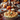 A close-up of a holiday-themed table showcases a shepherd's pie as the focal point. The pie, with its golden-brown topping and sprig of thyme, sits on a red and white checkered cloth. In the background, the table is adorned with pumpkins, autumn leaves, candles, and a glass of red wine, creating a festive and inviting scene.