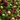 A close-up, vertically oriented image of a dense Christmas wall decoration. It features a rich tapestry of green pine needles and other foliage, interspersed with numerous ornaments, pinecones, and red berries. Prominent elements include large glittery gold spheres, deep red glittery spheres, matte and glossy green spheres, and various natural brown pinecones, creating a luxurious and festive visual texture that extends into a blurred background.