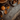 Overhead view of a Thanksgiving arrangement. A whole pumpkin pie and a slice of pie on a plate are displayed on a dark wooden surface. A small pumpkin, burlap, acorns, and scattered autumn leaves complete the festive scene.