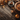 Overhead view of a rustic wooden table featuring a whole pumpkin pie on a wooden stand, a slice of pie on a plate with a fork, a small orange pumpkin, scattered autumn leaves in shades of gold and orange, and a few pinecones, all creating a cozy autumn scene.