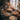 A high-angle view shows a wooden table laden with several pies of various flavors, sitting in front of a sunlit window. The pies are arranged artfully with pumpkins, dried flowers, and lit candles. The scene evokes a feeling of warmth, abundance, and autumn.