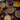 A top-down view displays a variety of pies on a dark, rustic wooden table. The pies include apple, pecan, cranberry, chocolate, and pumpkin, each with distinct crusts and fillings. Decorative elements such as small pumpkins, gourds, autumn leaves, and pinecones are scattered amongst the pies, creating a warm and inviting autumn-themed scene.