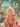 A vibrant digital painting depicts a young blonde woman with light skin, seen from the chest up, blowing a stream of iridescent bubbles in a sun-drenched park. She is wearing a yellow top and a red and white floral patterned open shirt, surrounded by numerous colorful bubbles floating against a background of lush green trees, a blue sky, and other people enjoying a picnic on the grass, evoking a joyful and carefree summer atmosphere.