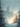 A fantastical winter scene depicts a grand, spired gothic castle in the distance, its windows faintly lit, shrouded in blue mist and gentle snowfall. Snow-covered evergreen trees frame the view, with a central Christmas tree glowing brightly with golden lights and bokeh effects, creating a magical and serene atmosphere.