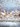 A festive vertical background image featuring a rustic, light-colored wooden plank surface in the foreground, with visible grain and texture. Above it, a dazzling display of blurred golden and soft blue circular bokeh lights glows softly, interspersed with numerous tiny, sparkling white glitter particles resembling falling snow. The overall impression is magical, elegant, and perfect for holiday or winter themes.