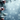 A vertical image showcasing snow-covered evergreen fir branches on the left side, featuring several rustic brown pine cones also dusted with white snow. The background is a soft, blurred expanse of icy blue with numerous white specks representing gently falling snow and soft bokeh lights. The overall scene evokes a peaceful and magical winter holiday atmosphere.