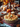 A close-up of a holiday-themed table showcases a shepherd's pie as the focal point. The pie, with its golden-brown topping and sprig of thyme, sits on a red and white checkered cloth. In the background, the table is adorned with pumpkins, autumn leaves, candles, and a glass of red wine, creating a festive and inviting scene.