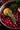 A close-up, overhead shot shows a dark metallic pot filled with a dark liquid, brimming with fresh ingredients. Numerous vibrant red cranberries and bright orange slices are submerged and floating, with several sprigs of fresh green rosemary layered on top. The background is softly blurred, showing a dark, rustic surface with a few more cranberries out of focus.