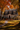 A gray two-story house is decorated for fall with pumpkins and a wreath on the front door. The lawn is covered in fallen autumn leaves. The trees surrounding the house are full of vibrant orange and yellow foliage, creating a warm and inviting atmosphere.