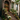 The image shows the entrance to a brownstone building, decorated for fall. Two wreaths hang on the wooden front door, and pumpkins and potted plants are arranged along the steps leading to the entrance. The steps have flowers and there are potted plants.
