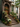 The image shows the entrance to a brownstone building, decorated for fall. Two wreaths hang on the wooden front door, and pumpkins and potted plants are arranged along the steps leading to the entrance. The steps have flowers and there are potted plants.