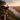 A lone hiker stands silhouetted on a rocky cliff edge, gazing out at a stunning landscape. Below, a valley is partially filled with a thick layer of fog, reflecting the soft colors of the sunrise. The scene evokes a sense of adventure, solitude, and the beauty of nature.