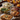 A Thanksgiving dinner is beautifully arranged on a rustic wooden table. The meal includes mashed potatoes topped with herbs, green bean casserole, sliced turkey garnished with thyme, and stuffing in clear glass baking dishes. The warm lighting and autumnal background create a cozy and inviting atmosphere, suggesting a traditional holiday gathering.