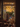 A medium shot photograph taken from inside a home looking out through an open glass doorway onto a family celebration on an outdoor patio. A table covered with food takes up most of the view, with several people around the table talking, while the warm sunlight filters through colorful autumn leaves on the trees outside. The scene has a warm and inviting atmosphere.