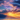 A breathtaking mountain landscape at sunrise. The sky is filled with colorful clouds of blue, purple, pink and orange while golden sunbeams shine through. A layer of fog covers the valley below with trees appearing on the hills.