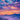 A vibrant landscape image shows mountain ranges at sunrise. The sky is filled with colorful clouds in shades of orange, pink, purple and blue. A thick mist fills the valley between the mountains, partially obscuring the ground and creating an ethereal effect.