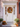 A white front door is decorated for autumn. A wreath of leaves, berries, and small pumpkins is centered on the door. Pumpkins, gourds, mums, and small potted plants adorn the steps leading to the door, creating a festive fall display.