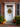 A beautifully decorated front door welcomes visitors for autumn. A white, paneled door with a decorative white frame features a fall wreath crafted from colorful gourds and leaves. Pumpkins and mums are arranged on the gray steps and brick walkway, adding to the festive atmosphere of the season.