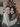 A close-up, vertical shot of two young women with radiant smiles, hugging each other warmly. They are looking directly at the camera, with a blurred, warmly lit Christmas tree visible in the background, creating a festive atmosphere.