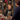 A smiling blonde woman, a shop assistant in a striped apron and dark green sweater, warmly assists a male customer at a wooden counter. The festive shop is decorated with Christmas garlands, red bows, and wrapped gifts, creating a cheerful holiday atmosphere. The woman's genuine smile and the cozy setting evoke a sense of excellent customer service and local retail charm during the holiday season.