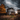 A dramatic shot depicts a weathered, two-story house with peeling paint, set against a backdrop of a stormy, cloudy sky. Golden autumn trees flank the house, and tall golden-brown grass fills the foreground. The scene evokes a sense of mystery and the beauty of decay.
