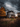 A dramatic shot depicts a weathered, two-story house with peeling paint, set against a backdrop of a stormy, cloudy sky. Golden autumn trees flank the house, and tall golden-brown grass fills the foreground. The scene evokes a sense of mystery and the beauty of decay.
