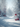A tranquil winter landscape captured with a shallow depth of field. In the foreground, three vibrant, textured red Christmas ornaments are nestled in fresh, pristine white snow and hang from a snow-dusted evergreen branch. The background features blurred, snow-covered trees, some adorned with small red berries, creating a magical and serene atmosphere with soft light and bokeh effects.