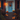 A warmly lit home entrance decorated for autumn and Halloween is shown. A blue door with a seasonal wreath is centered, flanked by a brick building with black shutters. The wooden steps are decorated with pumpkins, potted orange mums, and glowing lanterns containing candles, creating a cozy, inviting atmosphere.