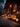 A festive Halloween scene features several carved pumpkins with glowing faces placed on the wooden porch of a log cabin. A lit candle sits inside a vintage-style lantern on the right and smaller lanterns are placed in the background. The warm orange light from the pumpkins and lanterns illuminates the scene against the dark blue sky, creating a cozy and inviting atmosphere.