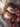 A young girl and boy, presumed to be siblings, are lying down on a white bed and laughing. The girl has long light brown hair, while the boy has short, light blonde hair. Both children are wearing matching red pajamas with a light-colored animal print, and sunlight illuminates their faces.