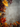 A top-down view of a textured gray concrete surface, framed on the left, top, and bottom by colorful autumn foliage, small red and orange berries on branches, and dried seed pods. The leaves exhibit a wide spectrum of fall colors including bright yellow, orange, red, and deep burgundy, providing a vibrant contrast against the neutral gray backdrop. The central area of the image is left open and clear, offering ample space for text or design elements.