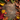 A top-down view of a rustic wooden surface framed by an abundance of colorful autumn foliage and natural elements. The border includes vibrant red, orange, yellow, and green leaves, bright red berries, various pinecones, and dark brown acorns, creating a warm, inviting seasonal frame around the central copy space.