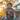 A Black man with a graying beard and glasses is smiling while carrying a young Black boy with curly hair on his shoulders. Both are looking towards the right and smiling broadly, with warm, golden light from the setting sun illuminating their faces and the blurred suburban background, conveying a sense of joy and familial love.