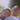 A low-angle close-up shows a man with glasses and a young boy sleeping peacefully side-by-side in a golden-colored hammock. The boy rests his head on the man's shoulder, both with eyes closed, bathed in warm, bright sunlight filtering through out-of-focus green trees in the background, creating a soft lens flare. The image conveys a tender moment of relaxation and familial bonding outdoors.