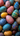A top-down, close-up view of numerous brightly colored, hand-painted eggs. The eggs feature diverse patterns of dots, swirls, and intricate designs in vibrant hues like deep blue, teal, magenta, yellow, and purple, filling the entire frame. This image conveys a festive and artistic atmosphere, perfect for celebrating holidays or traditional craftsmanship.
