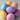 A close-up shot of a small pile of decorative speckled eggs in various pastel colors, including light yellow, pale blue, lavender, and soft pink. The eggs are stacked loosely against a minimalist, light gray background, with soft lighting highlighting their gentle textures and shades.