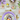 An overhead view displays a beautifully set Easter dining table with a focus on a single place setting. A lavender scalloped charger plate holds a white dinner plate decorated with delicate spring flowers and a small bird's nest containing four pastel Easter eggs. Gold cutlery with floral-patterned handles, along with other decorative eggs, a small ceramic sheep, and fresh purple flowers, are arranged on a rustic white wooden tabletop, conveying a bright, festive, and springtime holiday atmosphere.