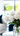 A close-up, vertical shot of a beautiful bouquet of white peonies with green stems, arranged in a clear glass vase on a white table. The background is a brightly lit, out-of-focus modern living room, featuring a cream sofa with a deep teal velvet cushion and a large window looking out onto green foliage. The image evokes a feeling of freshness, elegance, and serene luxury.