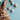 A fluffy brown and white Easter bunny peeks up from the bottom left of the frame, looking forward with its nose and one dark eye visible. It's set against a light teal background, which is adorned with several pastel speckled Easter eggs in peach, light blue, and off-white tones, along with a scattering of tiny colorful sprinkles. The composition is a flat lay, with the bunny taking up the lower portion and the eggs/sprinkles spread across the upper and right side of the image.